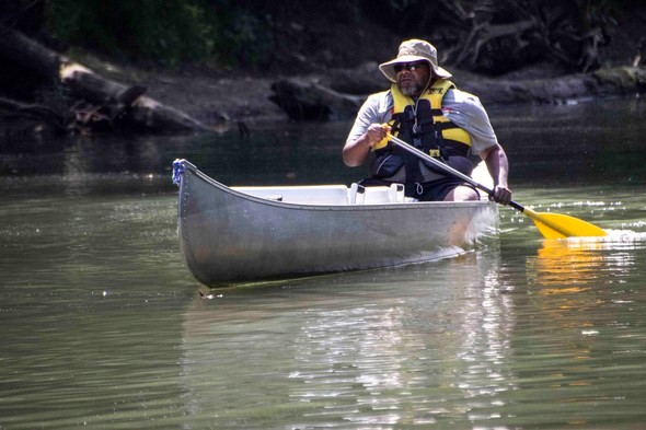 Man paddles canoe on stream