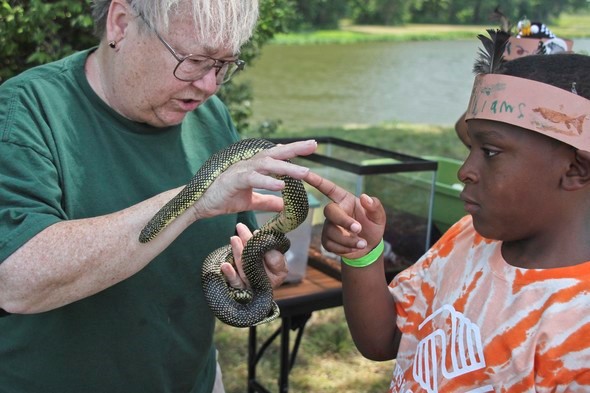 An MDC staff member shows a snake to a young girl.