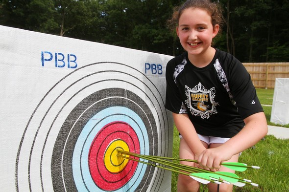 Young girl stands next to archery target