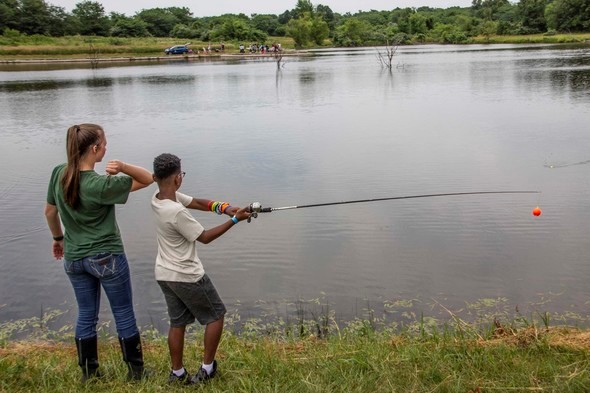 Staff and boy fishing at lake