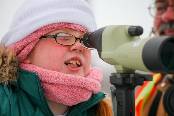Girl looks for bald eagles using spotting scope