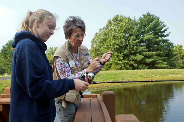 Volunteer helps girl to fish