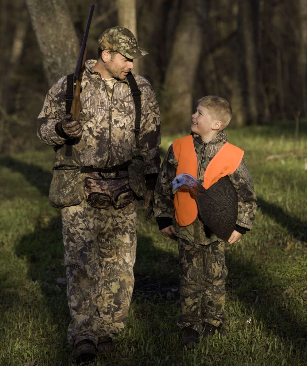 man and boy walking in woods with turkey decoy