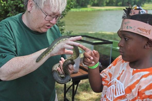 An MDC staff member shows a snake to a young girl.
