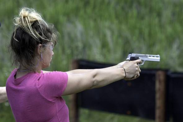 A woman shoots a handgun at a shooting range.