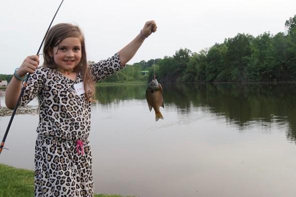 A little girl poses with a fish she caught at a Columbia pond.