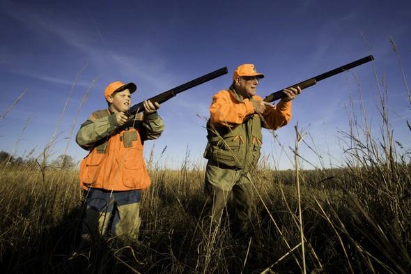 A boy and his grandfather aim their guns in hopes to bag a bird.