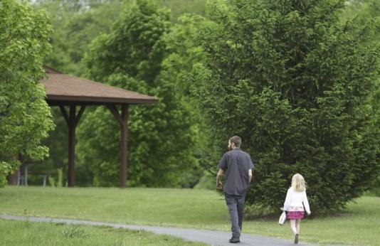 Father and daughter walk in city park