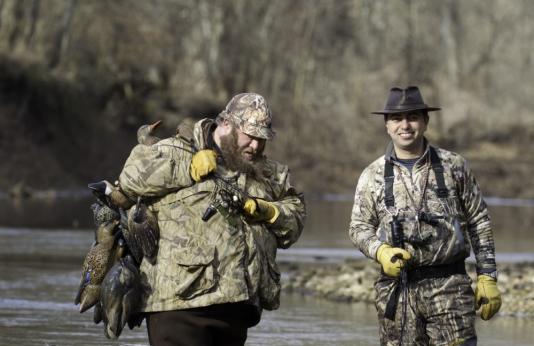 Two waterfowl hunters with dog and decoys