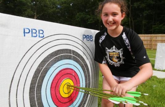 Young girl stands next to archery target
