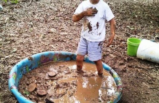 boy playing in pool of mud