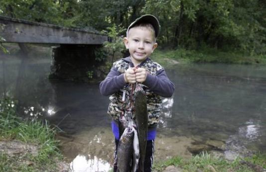 Kid holding up trout.