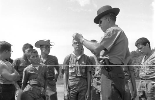 A conservation agent speaks with a group of boy scouts in the 1950s.