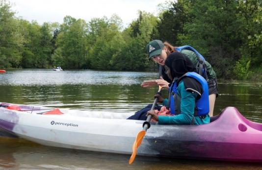 An MDC instructor teaches a girl how to kayak.