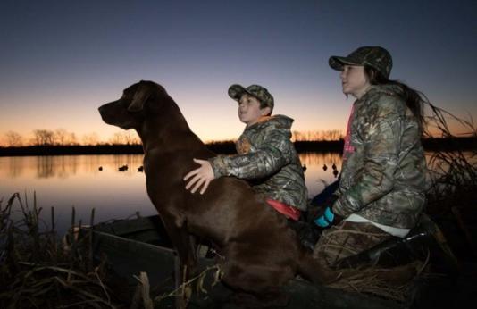 two kids duck hunting with dog