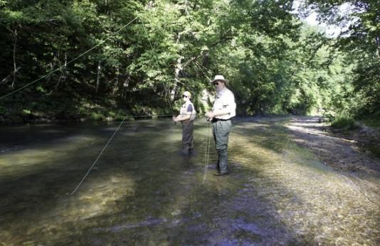 two people fly fishing in stream