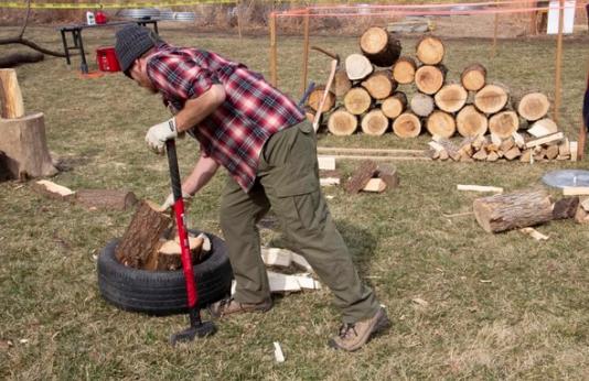 A man chops wood at an Urban Woodsman program